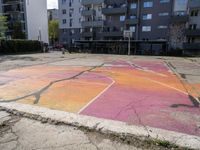 an empty parking lot painted with colorful paints on it and the grass in front is empty