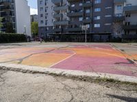 an empty parking lot painted with colorful paints on it and the grass in front is empty