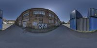 a fisheye lens shows a skateboarder on the ramp with a building in the background