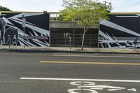 a black and white street with graffiti writing on it, along side a bike lane