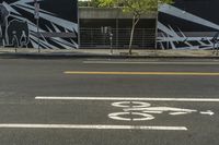 a black and white street with graffiti writing on it, along side a bike lane