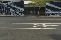 a black and white street with graffiti writing on it, along side a bike lane