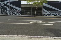 a black and white street with graffiti writing on it, along side a bike lane