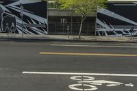 a black and white street with graffiti writing on it, along side a bike lane