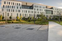 a city street surrounded by grass and tall buildings at the end of a street there is a paved pathway in front of the building