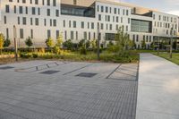 a city street surrounded by grass and tall buildings at the end of a street there is a paved pathway in front of the building