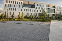 a city street surrounded by grass and tall buildings at the end of a street there is a paved pathway in front of the building