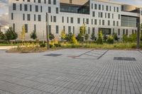 a city street surrounded by grass and tall buildings at the end of a street there is a paved pathway in front of the building