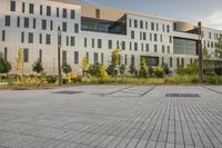 a city street surrounded by grass and tall buildings at the end of a street there is a paved pathway in front of the building