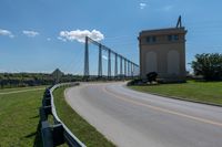 a bridge with two long towers in the distance is seen behind the road to the side