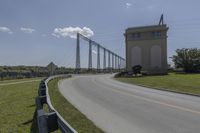 a bridge with two long towers in the distance is seen behind the road to the side