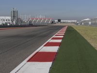 an empty track at a motorsports club with some red and white stripeing on it