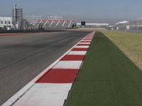 an empty track at a motorsports club with some red and white stripeing on it