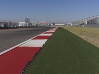 an empty track at a motorsports club with some red and white stripeing on it