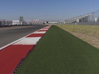 an empty track at a motorsports club with some red and white stripeing on it