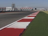 an empty track at a motorsports club with some red and white stripeing on it