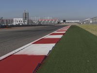 an empty track at a motorsports club with some red and white stripeing on it