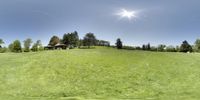 a panoramic picture of a home sits in a grassy field with trees and other houses