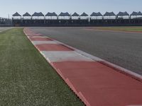 an empty track at a motorsports club with some red and white stripeing on it