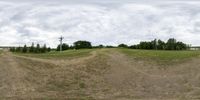 this is a panorama of a grassy field near power lines and telephone poles in the distance