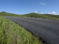 the grass grows in between the roadway and road area of a rural area under a bright blue sky