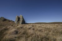 an image of a beautiful grassy landscape with rocks in it and a blue sky in the background