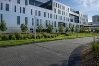 a city street surrounded by grass and tall buildings at the end of a street there is a paved pathway in front of the building