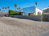 a gravel lot in front of a building with palm trees lining the sides and top