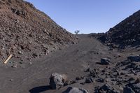 a gravel mountain with a sign sticking out of it's side next to rocks and trees