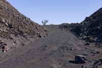 a gravel mountain with a sign sticking out of it's side next to rocks and trees