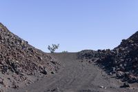 a gravel mountain with a sign sticking out of it's side next to rocks and trees