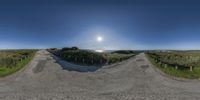 360 - angle shot of a gravel road surrounded by hills and a blue sky,