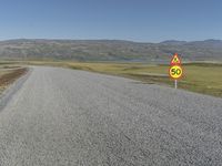 a road with gravel and a speed limit sign that says 65 degrees down on it