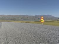 a road with gravel and a speed limit sign that says 65 degrees down on it