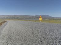 a road with gravel and a speed limit sign that says 65 degrees down on it