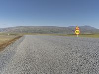 a road with gravel and a speed limit sign that says 65 degrees down on it