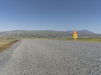 a road with gravel and a speed limit sign that says 65 degrees down on it