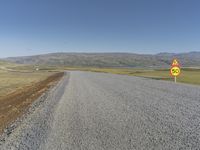 a road with gravel and a speed limit sign that says 65 degrees down on it