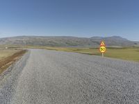 a road with gravel and a speed limit sign that says 65 degrees down on it