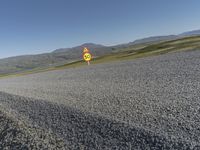 a speed limiter sign on a gravel road with mountains in the distance behind it