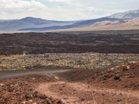 gravel road winding through barren terrain into the distance of mountain range and hills in the background