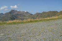 a person walking with an umbrella and suitcase on a gravel road on a mountain top