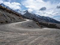 a gravel road in front of snowy mountain ranges on a partly cloudy day - zofran bielove