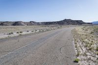 a gravel road running between some hills with a blue sky in the background behind it