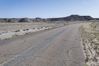 a gravel road running between some hills with a blue sky in the background behind it