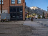 a red fire hydrant sitting in front of an old store window and building next to an open air field