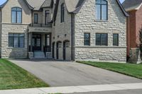 a gray and brick house on the corner of a sidewalk with grass in front of it