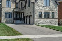 a gray and brick house on the corner of a sidewalk with grass in front of it