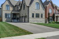 a gray and brick house on the corner of a sidewalk with grass in front of it