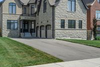 a gray and brick house on the corner of a sidewalk with grass in front of it